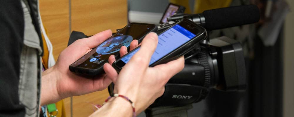 Student working with two mobile devices and video equipment